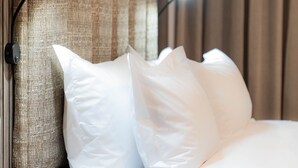 A neatly made bed with white linens, a textured headboard, and a bedside table with a lamp. - Zar Hotel (Kingsburgh)