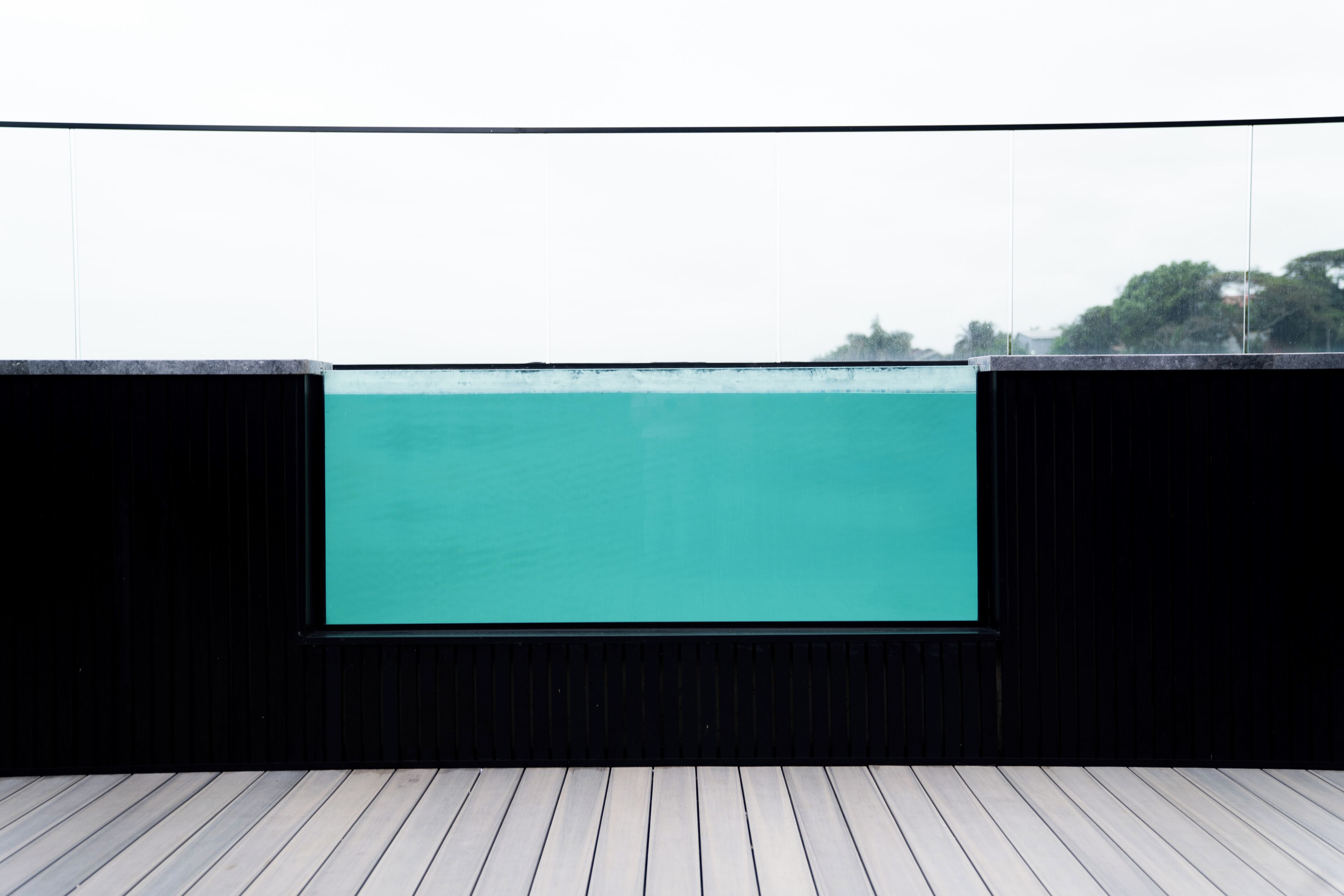 A view of a swimming pool with a wooden deck in the foreground.