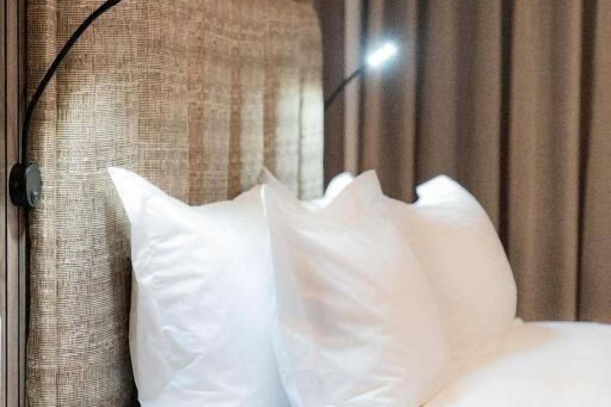 Une chambre d’hôtel avec une tête de lit, une table de chevet et un lit avec du linge de lit blanc.
