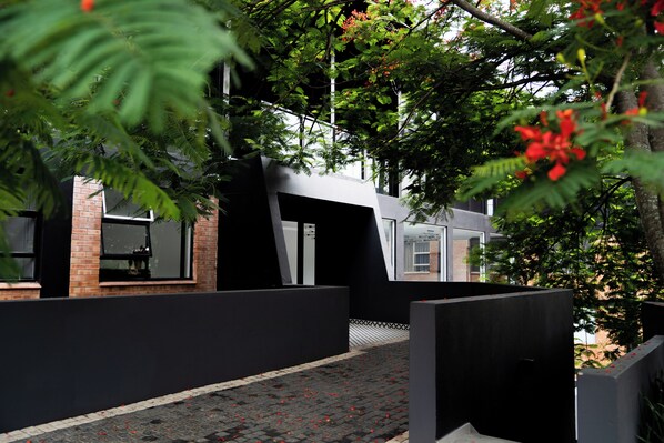A modern building with a black facade, large windows, and a brick section.