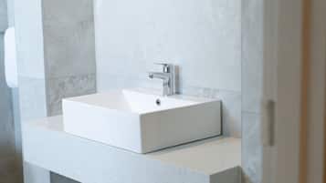 A modern bathroom with a rectangular white sink, chrome faucet, and a speckled countertop.