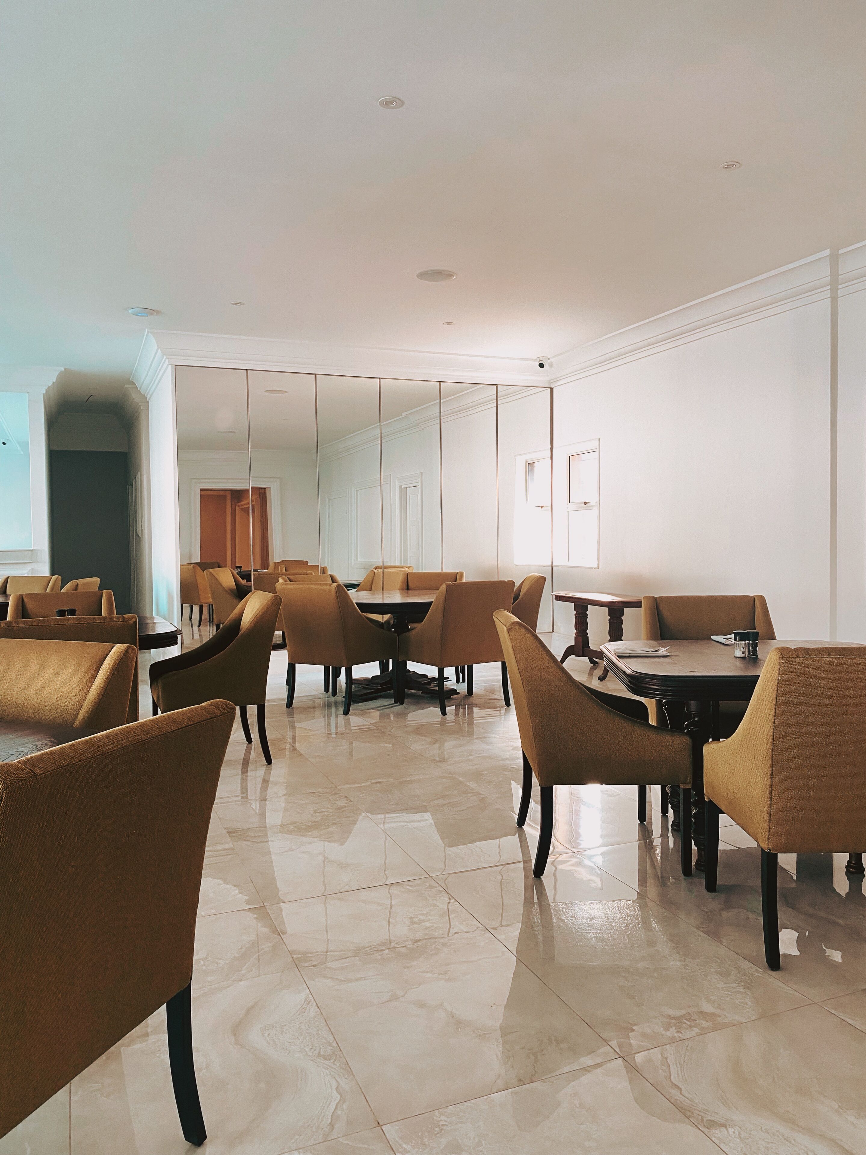 A spacious dining area with high ceilings, polished marble floors, and modern furniture.