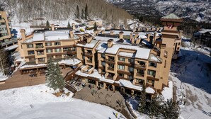 Ein mehrstöckiges Hotel mit Balkonen, einer Seilbahn und einem Berg im Hintergrund.