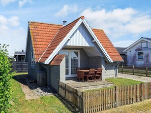 A small house with a tiled roof, a wooden deck, and a fenced yard. - 4 Person Holiday Home in Karrebaeksminde (Karrebæksminde)