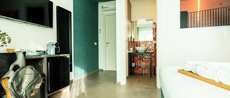 Une chambre d’hôtel avec un lit, un bureau, une chaise, une télévision et une salle de bain visible à travers une porte ouverte.