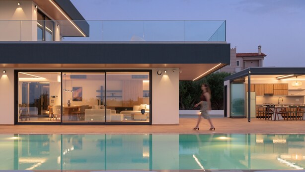 Una casa moderna con piscina, grandes puertas de cristal y un comedor.