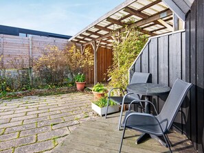 A patio with a wooden pergola, two metal chairs, and potted plants. - 6 Person Holiday Home in Borkop (Borkop)