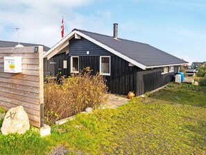 A single-story building with a dark exterior, a chimney, and a small porch area.