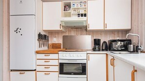 Une cuisine compacte équipée d’un réfrigérateur, d’une cuisinière, d’un four, d’un four à micro-ondes et d’une machine à café.