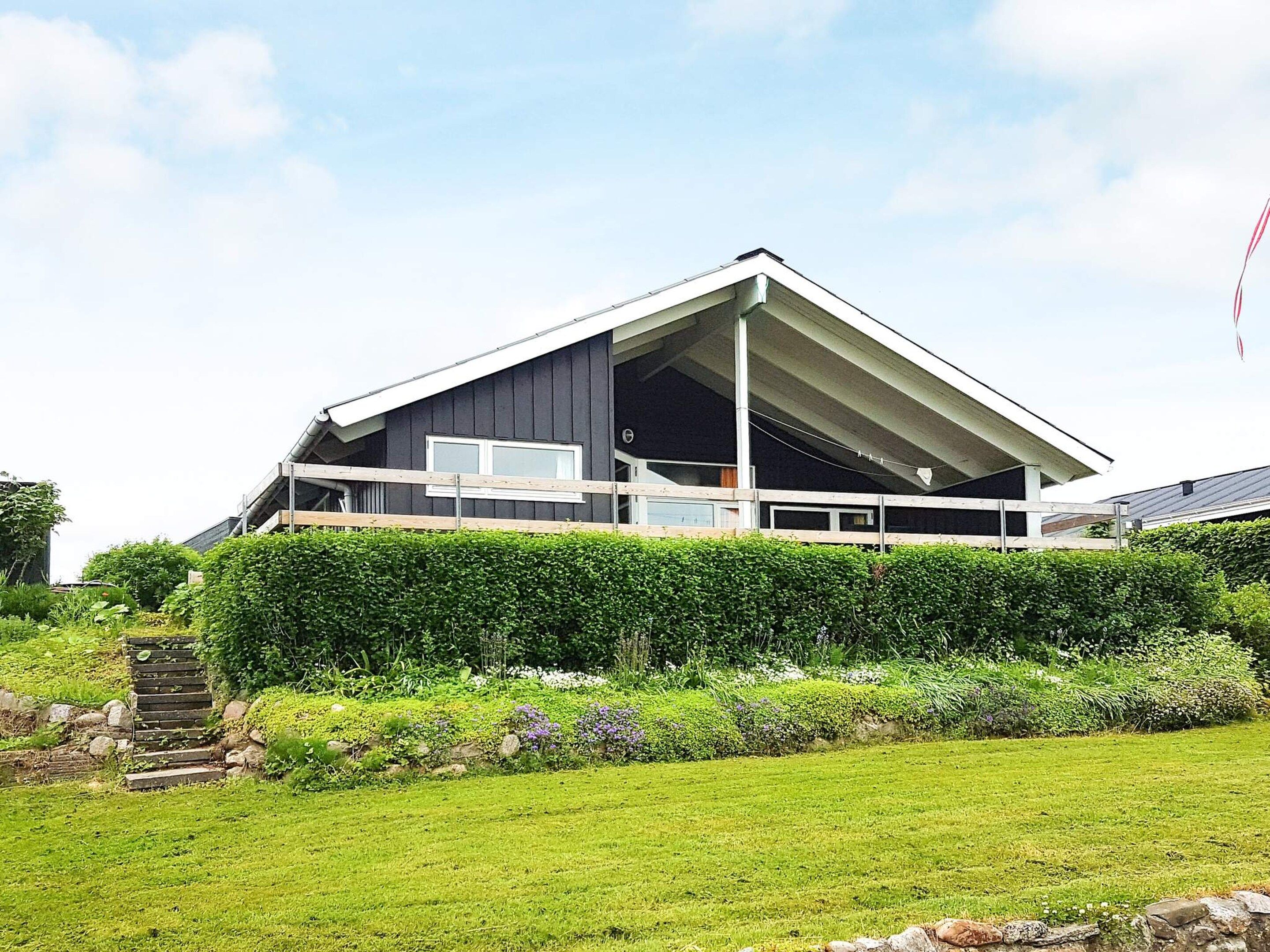 A modern house with a sloped roof, a balcony, and a well-maintained garden.
