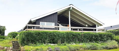 A modern house with a sloped roof, a balcony, and a well-maintained garden.