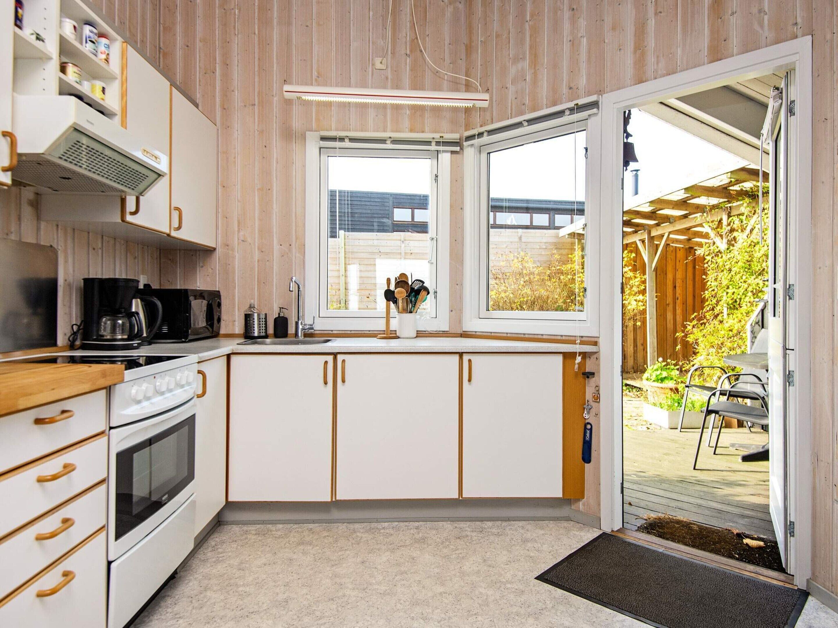 A compact kitchen with white cabinets, a stove, and a coffee maker.