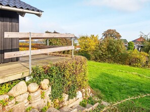 A wooden deck with a stone wall and a grassy lawn. - 6 Person Holiday Home in Borkop-by Traum (Borkop)