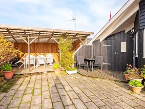 A covered outdoor seating area with two sets of chairs, a wooden pergola, and potted plants. - 6 Person Holiday Home in Borkop (Borkop)