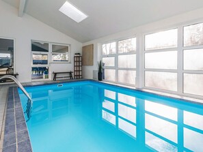 A swimming pool with a view of the outdoors, a bench, and a ladder.