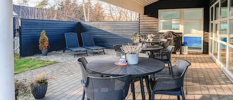 An outdoor patio with a round table and chairs, a small potted plant, and a covered seating area.