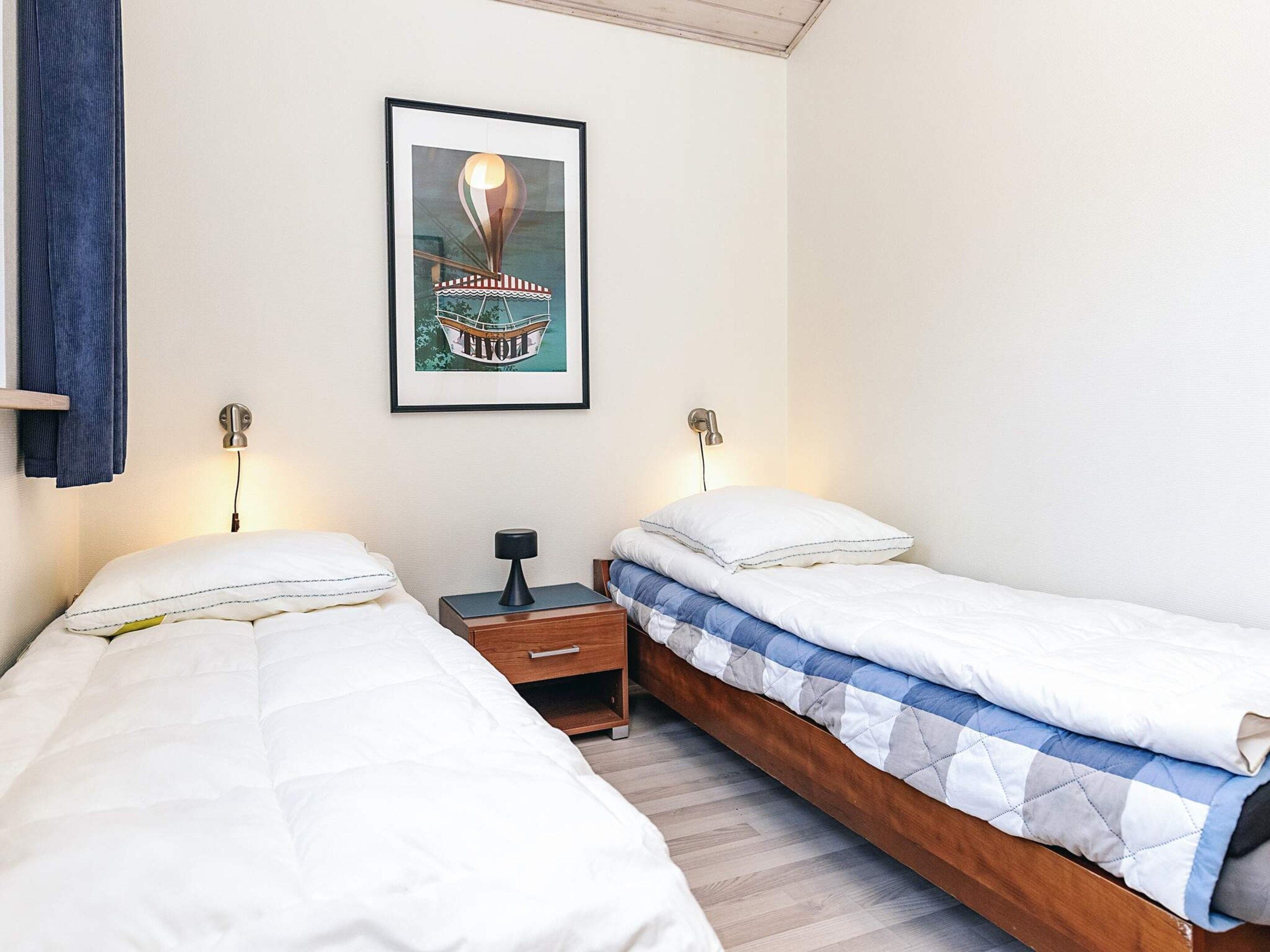Un dormitorio con dos camas, un cuadro enmarcado en la pared y lámparas de noche.