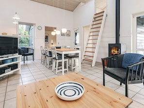 Una sala de estar moderna con una mesa de comedor de madera, un televisor y una chimenea.