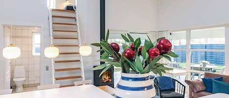 Un interior moderno con una escalera blanca, un comedor y un ventanal con vistas al exterior.