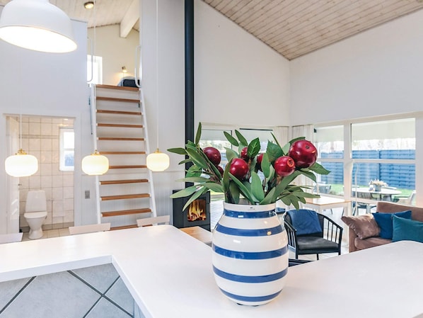 Un interior moderno con una escalera blanca, un comedor y un ventanal con vistas al exterior.