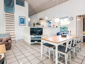 A modern kitchen with a wooden table and chairs, a TV, and pendant lights. - 4 Star Holiday Home in Vaeggerlose (Vaeggerlose)