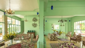 Un salón amplio con mobiliario estampado con motivos florales, una mesa de centro de cristal y una araña.