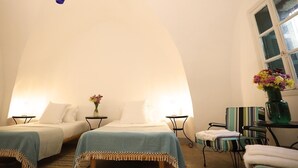 Una habitación acogedora con dos camas, una mesita con un florero y una silla.