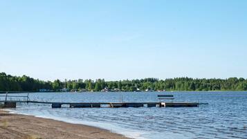 A lakeside view with a dock extending into the water, surrounded by a forested area.
