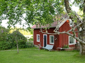 A red wooden house with a sloped roof, a front door, and a small porch area. - 4 Star Holiday Home in Nassjo (Nassjo)