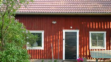 A red building with a tiled roof, a black door, and two windows.