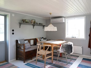 A cozy room with a wooden bench, a dining table, and a chair. There is a window providing natural light, a ceiling fan, and a radiator. - 4 Star Holiday Home in Nassjo (Nassjo)