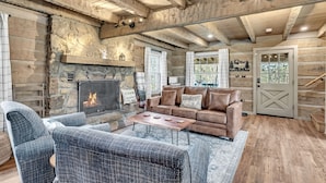 L’intérieur chaleureux d’un chalet en bois, avec une cheminée en pierre, un canapé en cuir et un plafond en bois rustique.