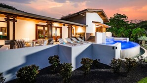 Ein modernes Haus mit Pool, Sitzgelegenheiten im Freien und einem gepflegten Garten.