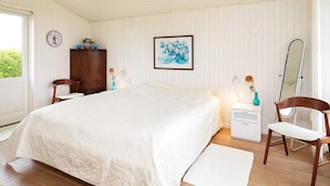 A bedroom with a large bed, a wooden wardrobe, a desk, a chair, a mirror, and a clock on the wall. - 6 Person Holiday Home in Brenderup Fyn (Middelfart)