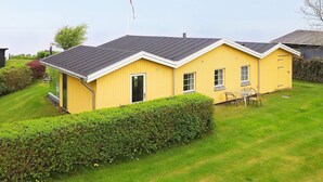 A yellow building with a dark roof, a door, and windows. There is a hedge in front and a grassy area around. - 6 Person Holiday Home in Brenderup Fyn (Middelfart)