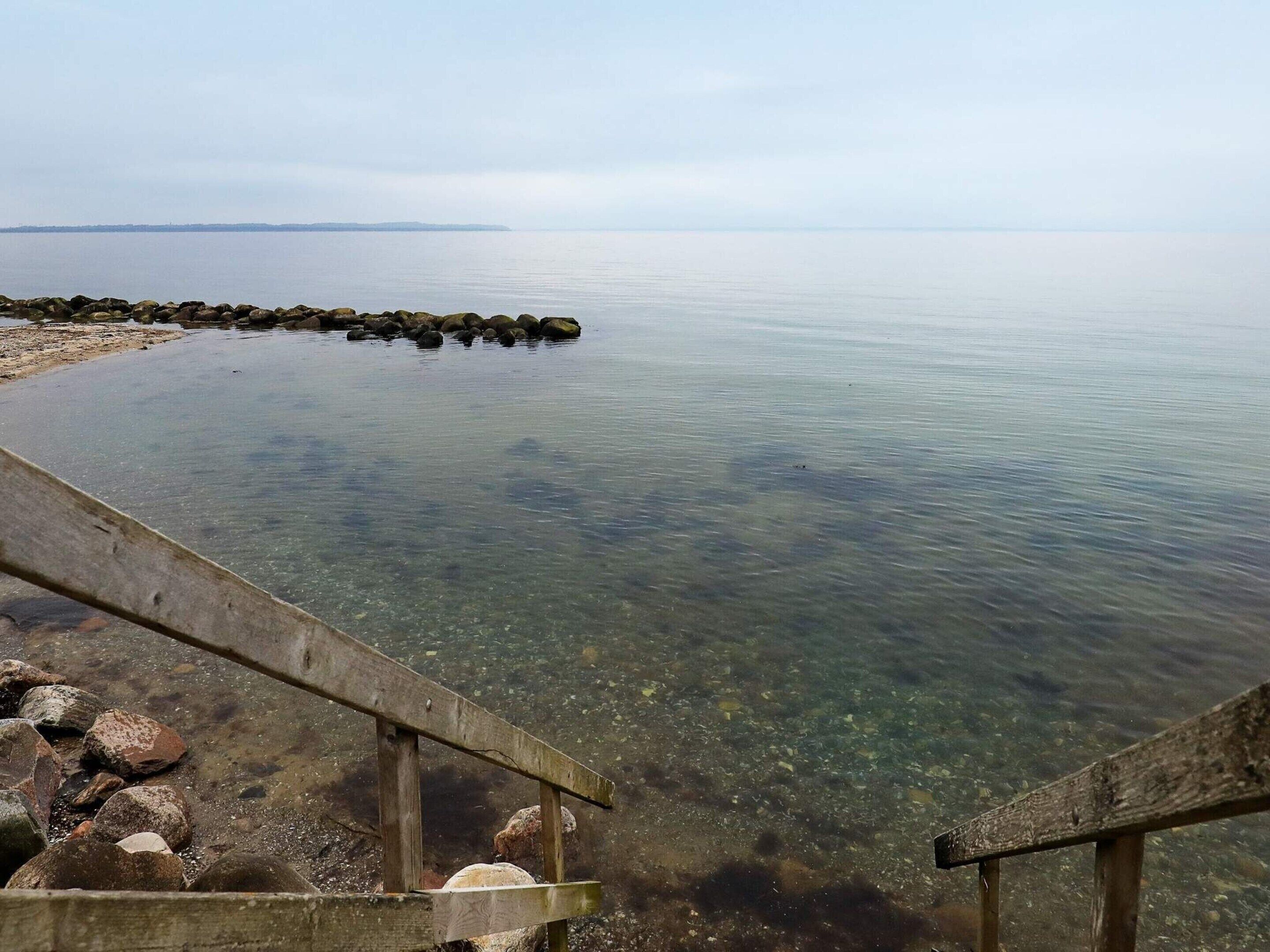 A clear view of a calm body of water with a wooden pier extending into it.
