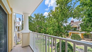A balcony with a white railing, a view of a residential area with trees and houses, and a clear blue sky. - Seven Eagles Orchid: Water Park, Mini-Golf, Golf and More! (Kissimmee)