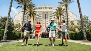A group of people walking on a golf course with a large hotel in the background. - Seven Eagles Orchid: Water Park, Mini-Golf, Golf and More! (Kissimmee)