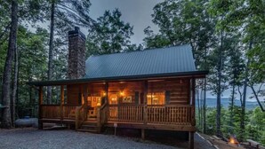 A cabin with a wooden exterior, a stone chimney, and a porch with steps leading to the entrance. - Misty Ridge - Where pets are pampered amidst stunning mountain panoramas, with outdoor fireplace, hot tub, firepit, pool table, and WiFi (Ellijay)