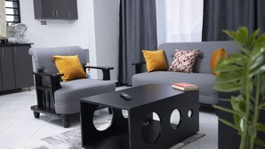 A modern living room with a grey sofa, two armchairs, a black coffee table, and a small side table. - Peaceful space, with unlimited Wi-Fi internet and free parking at the premises.. (Kampala)