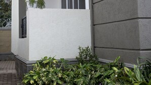 A modern building with a white exterior, a balcony with potted plants, and a brick pathway. - Peaceful space, with unlimited Wi-Fi internet and free parking at the premises.. (Kampala)