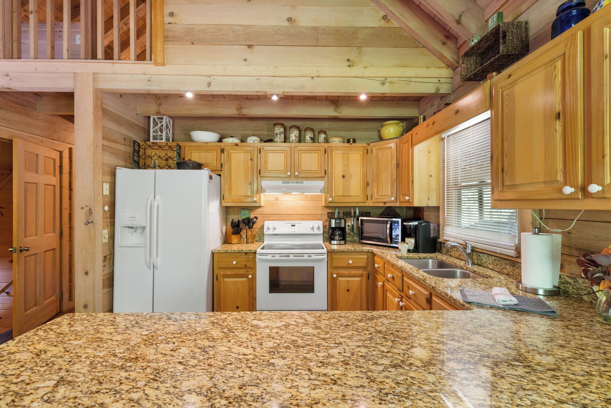 A kitchen with wooden cabinets, a white refrigerator, a stove, and granite countertops.