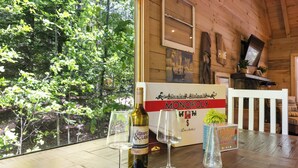 Un interior de madera con una mesa mostrando una botella de vino, dos copas y una caja con la etiqueta 'Monopoly'.