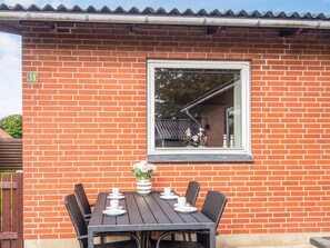 A brick building with a window, a table with chairs, and a potted plant. - 4 Person Holiday Home in Oksbol (Oksbol)