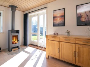 Una habitación con estufa de leña, un armario de madera y una puerta de cristal que da a un balcón.