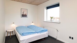 Ein Schlafzimmer mit einem Bett, einem Nachttisch, einem Fenster mit Blick und einer Heizung.