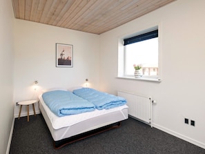 Una camera da letto con un letto, un comodino, una finestra vista radiatore.