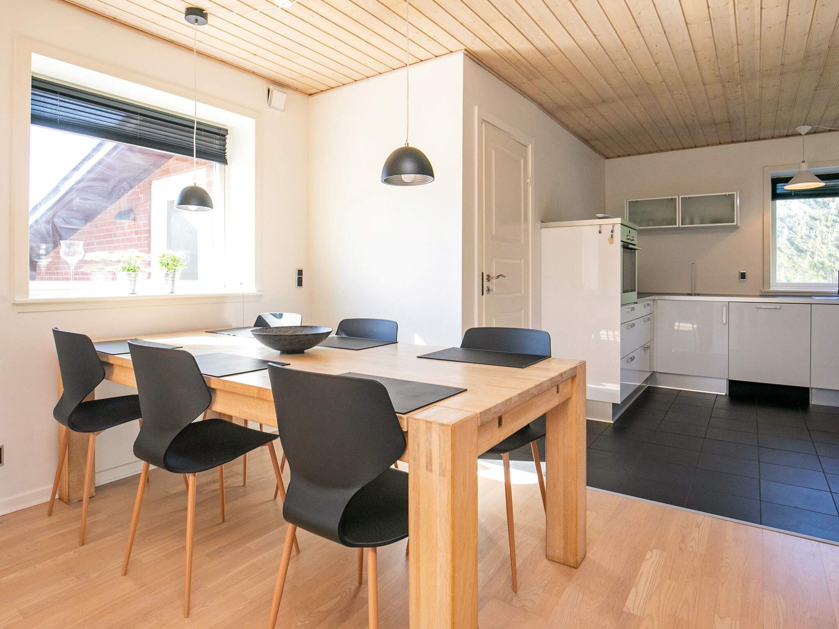 Eine moderne Küche mit weißen Schränken, einem Holztisch und schwarzen Stühlen.