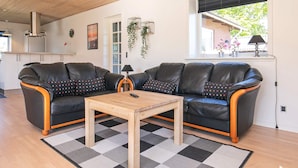 Ein modernes Wohnzimmer mit zwei schwarzen Ledersofas, einem Holztisch und einem karierten Teppich.