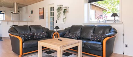 A modern living room with two black leather sofas, a wooden coffee table, and a checkered rug.